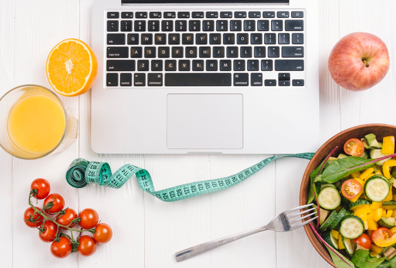 Una Vista Aerea De La Laptop Con Ensalada Fresca Frutas Jugo Y Tomates Cherry En El Escritorio De Madera Blanca Una Vista Aerea De La Laptop Con Ensalada Fresca Frutas Jugo Y Tomates Cherry En El Escritorio De Madera Blanca